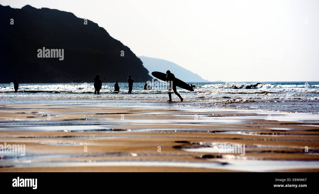 Un uomo che porta una tavola da surf sulla spiaggia a Perranporth Cornwall Inghilterra Regno Unito Foto Stock