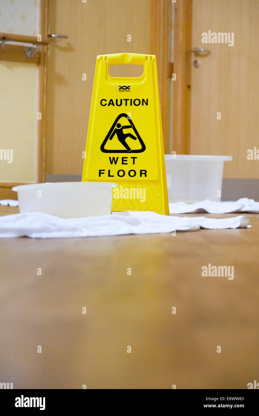 Vaschette di raccolta e il pavimento è scivoloso / Pericolo di scivolamento / pavimento bagnato segno dove il tetto perde acqua che gocciolava su un ospedale NHS piano. Regno Unito Foto Stock