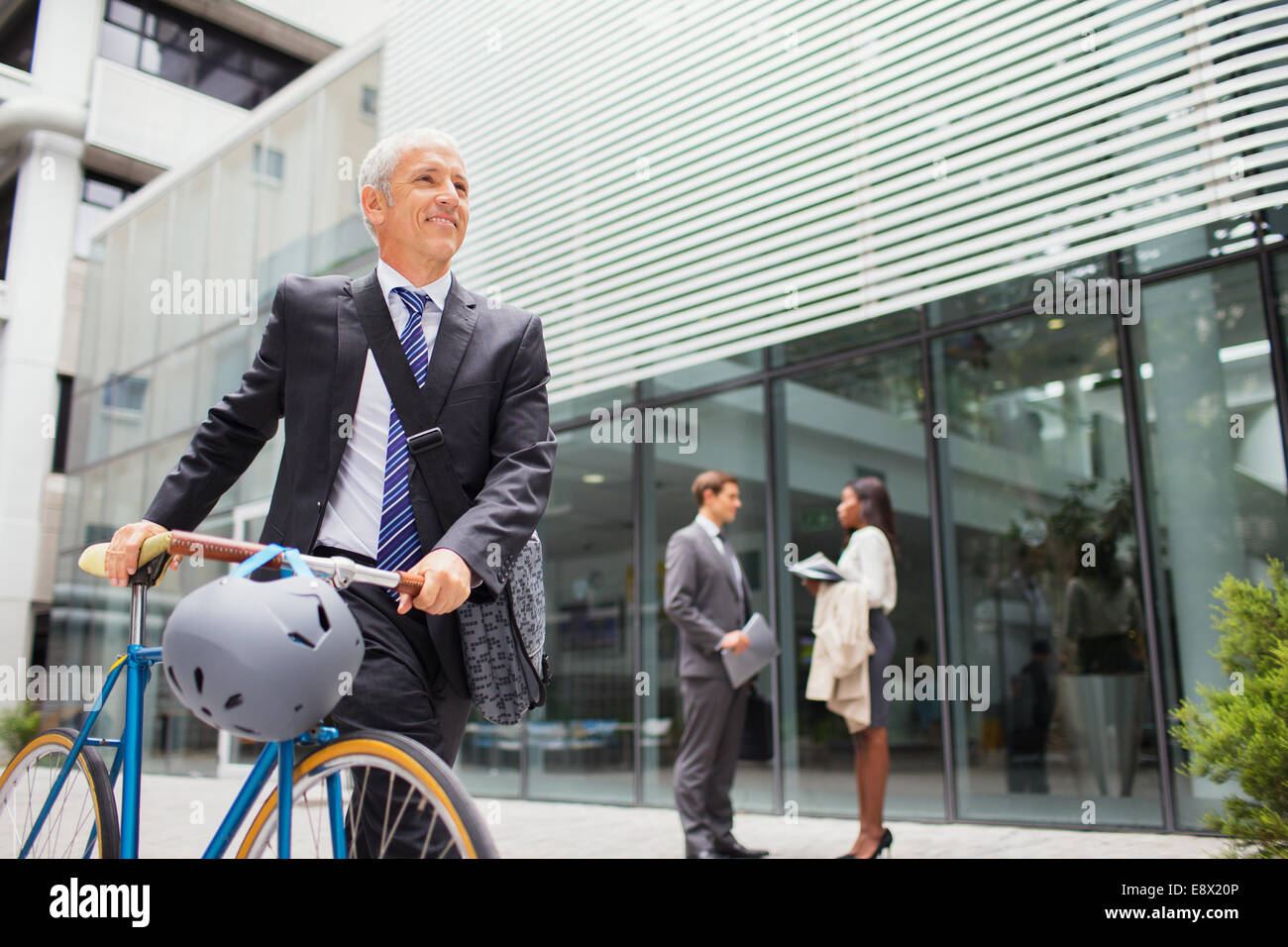 Imprenditore bicicletta a piedi al di fuori dell'edificio degli uffici Foto Stock