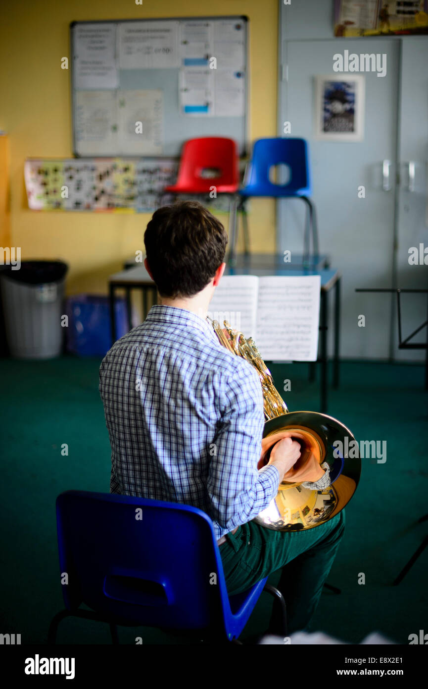 Un giovane musicista maschio practicising corno francese in classe la lezione di educazione musicale parte officina di Aberystwyth MusicFest 2014 Foto Stock