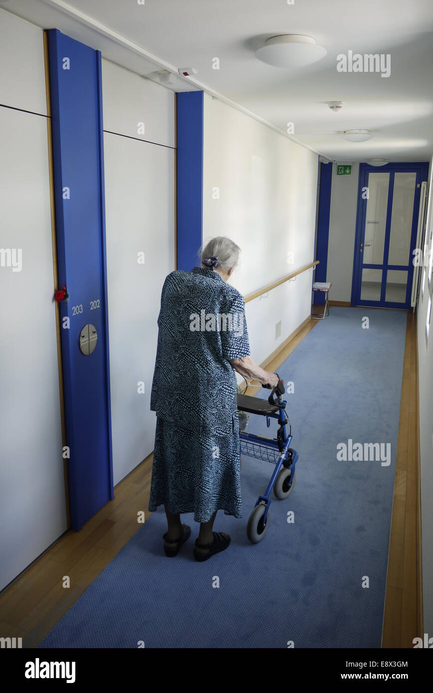 Betagte Altersheim-Insassin allein mit Gehhilfe - solitario donna residente in casa di riposo per anziani con laminazione walker Foto Stock