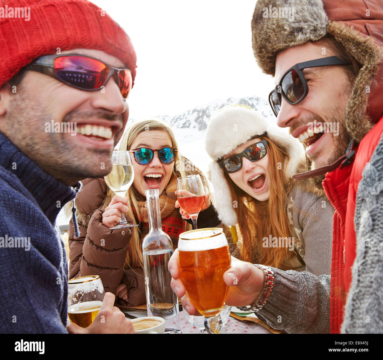 Amici celebrando con bevande nella neve Foto Stock
