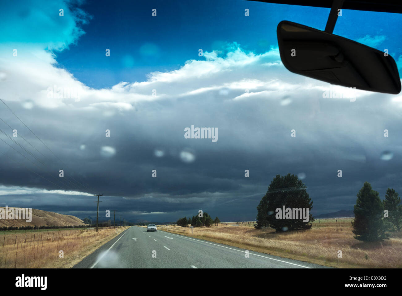 Nuova Zelanda meteo possono essere imprevedibili. La guida in un acquazzone su autostrada 8 vicino a Omarama. Prime gocce di pioggia sul parabrezza Foto Stock