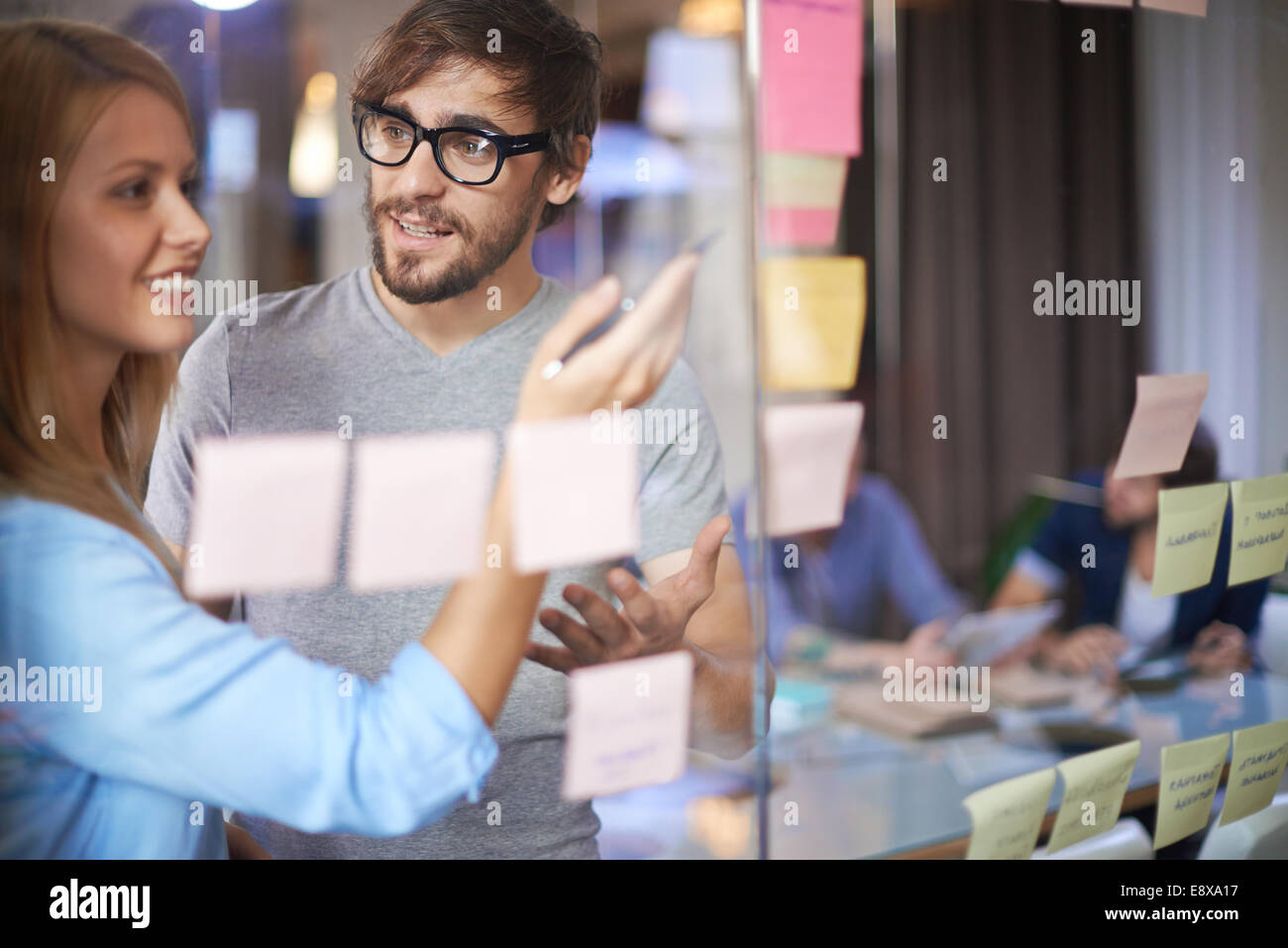 Maschio e femmina di colleghi che hanno discusso sulle note di promemoria di carta in ufficio Foto Stock