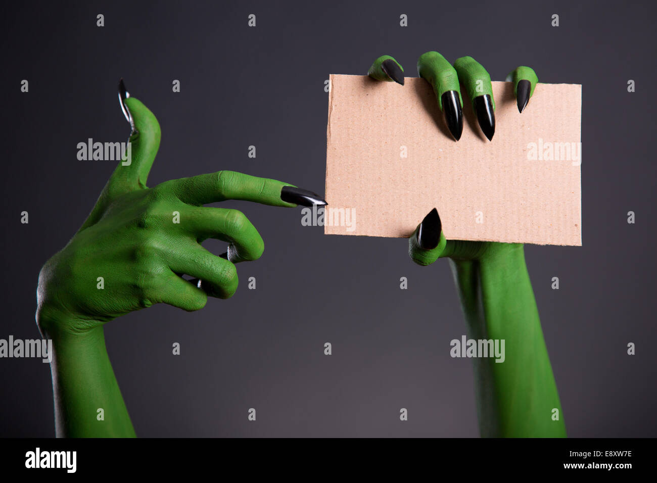 Green monster mano con unghie nere puntando sul pezzo di cartone, tema Halloween Foto Stock