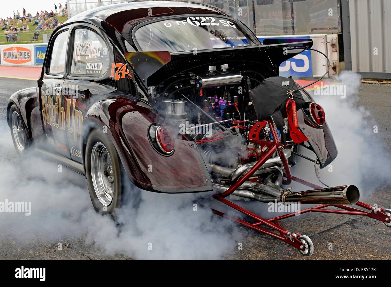 VW Beetle dragster esecuzione di burnout sulla linea di partenza di Santa Pod raceway Foto Stock