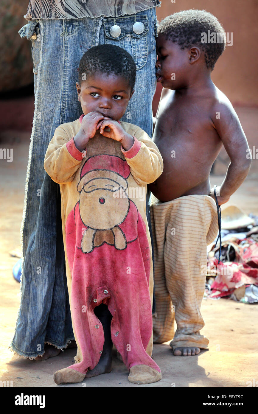 Triste ragazzo vestito in un body che mostra di Babbo Natale di seconda mano panno. Zambia, Africa Foto Stock