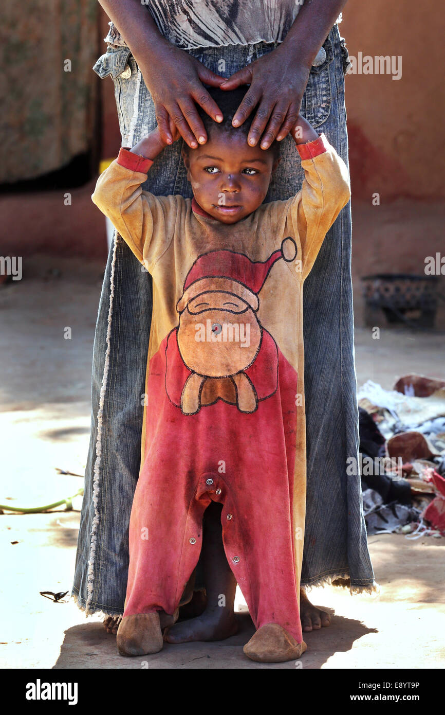 Triste ragazzo vestito in un body che mostra di Babbo Natale di seconda mano panno. Zambia, Africa Foto Stock
