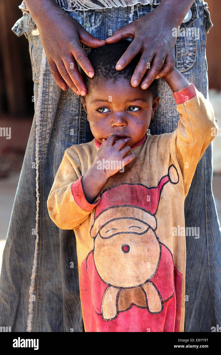 Triste ragazzo vestito in un body che mostra di Babbo Natale di seconda mano panno. Zambia, Africa Foto Stock