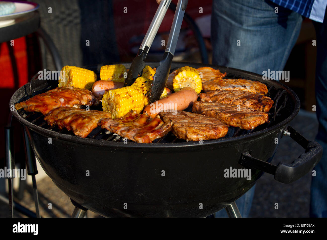 Barbecue con salsiccia, mais e carne su Foto Stock