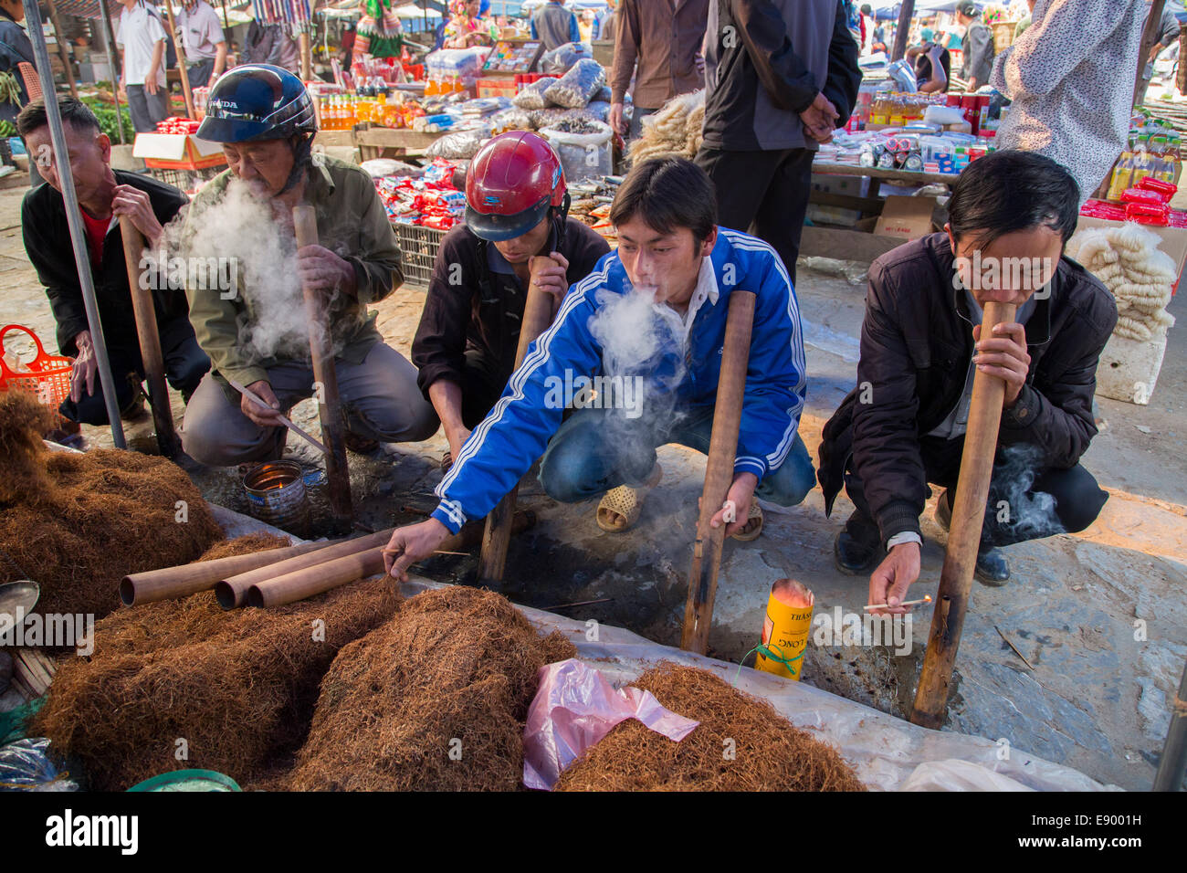 Il vietnamita della tribù della collina uomini Hmong in corrispondenza può cau Market il tabacco da fumo in tubi di bambù Foto Stock