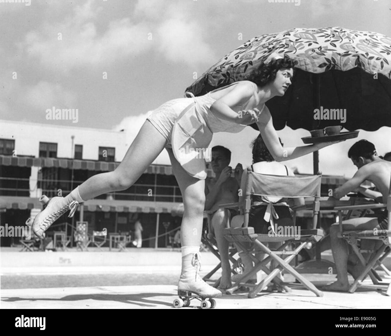 Una fotografia di una cameriera di pattinaggio a rotelle al Roney Plaza di Miami Beach, scattata il 2 febbraio 1939. L'immagine cattura la vivace atmosfera da pranzo all'aperto, con sedie pieghevoli, ombrelloni e una piscina. Foto Stock