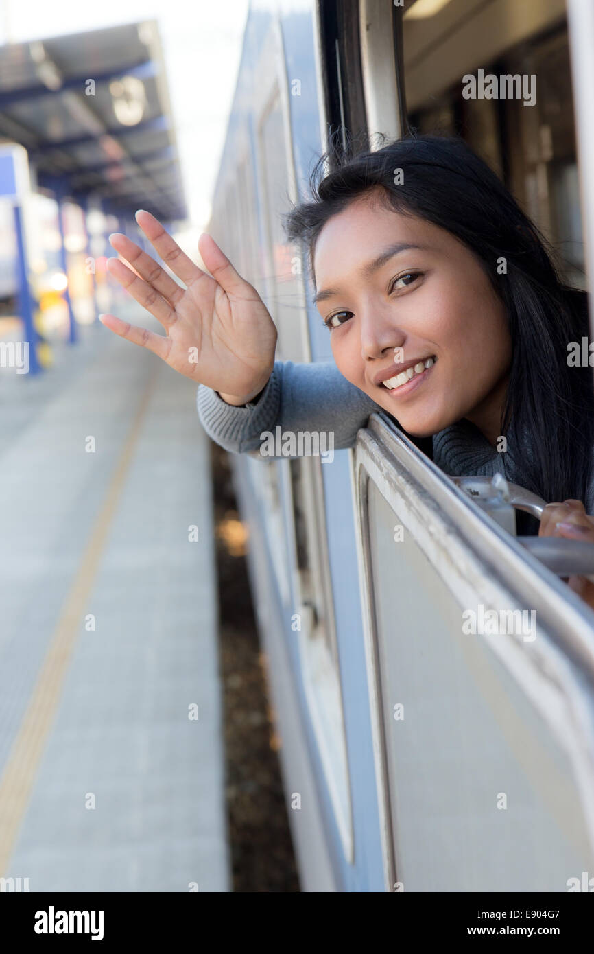 Donna sventolare un saluto dal movimento del treno Foto Stock