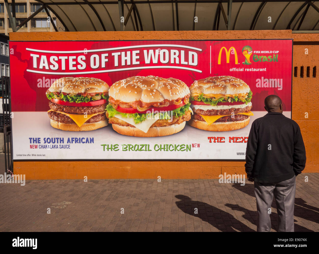 JOHANNESBURG, SUD AFRICA - ristorante McDonald's billboard e l'uomo. I sapori del mondo hamburger promozione. Foto Stock