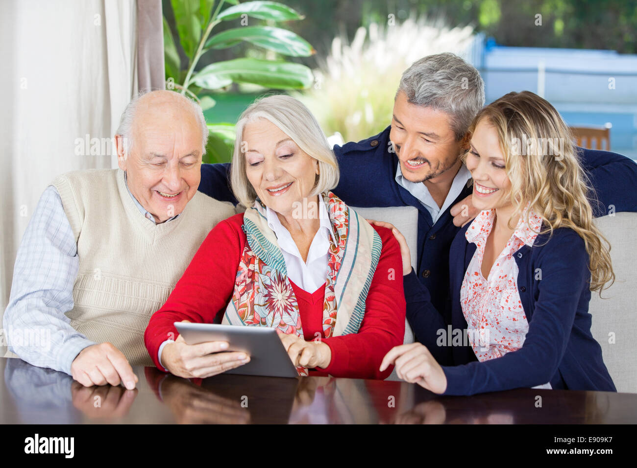 Nipoti guardando i nonni con tavoletta digitale Foto Stock