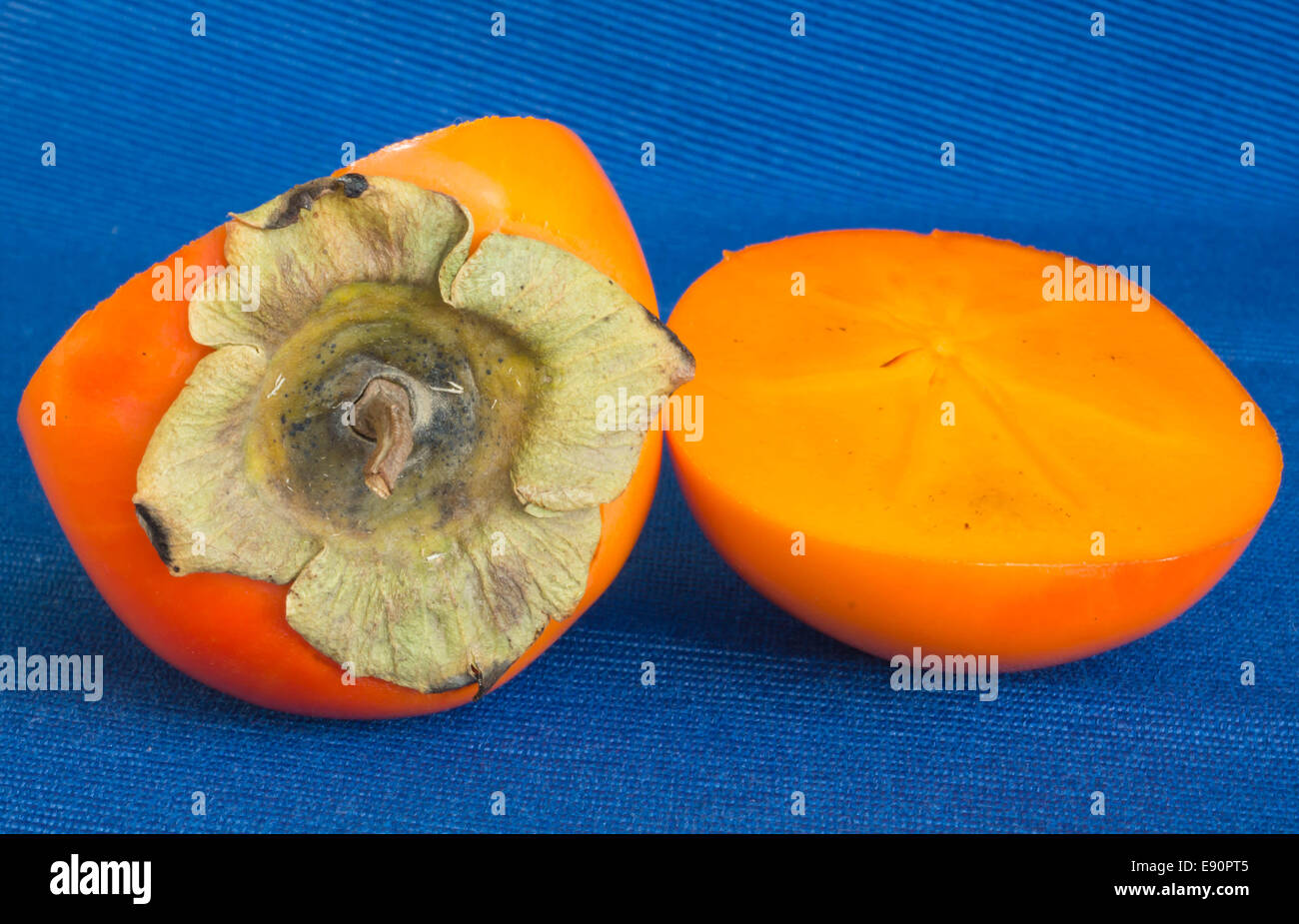 Due metà di un persimmon su uno sfondo blu Foto Stock