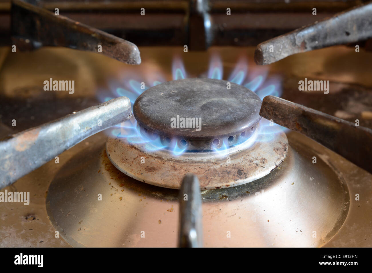 Fiamma blu su una domestica fornello a gas anello. Sporchi con spruzzi di cibo. Foto Stock