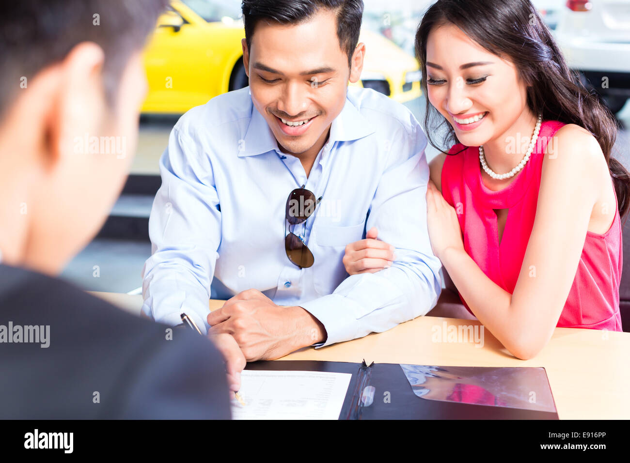 Asian giovane firma del contratto di vendita per auto presso la concessionaria Foto Stock