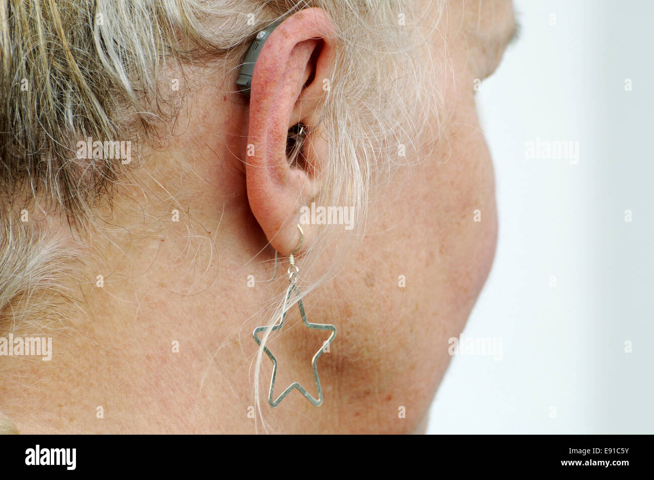 Moderno piccolo hearing aid dietro l'orecchio di una donna Foto Stock