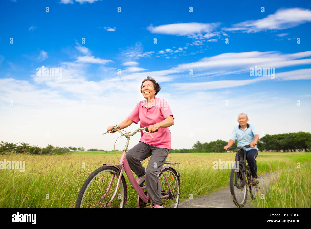 Felice Asian anziani anziani matura mountain bike in fattoria con cielo blu sullo sfondo Foto Stock