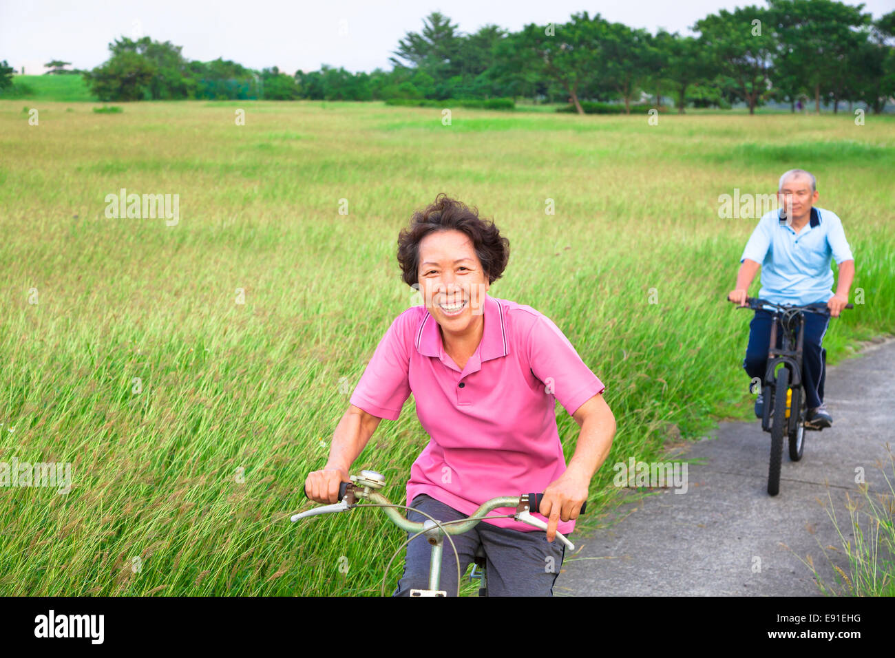 Felice seniors asiatica giovane mountain bike nel parco.Le pensioni di anzianità e di uno stile di vita sano concetto Foto Stock