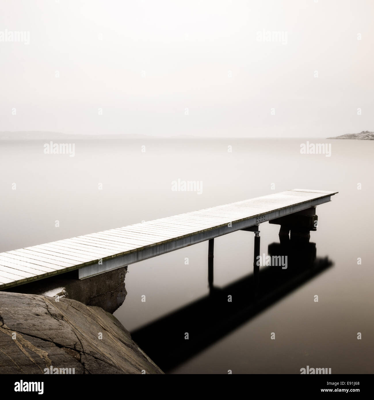 Il molo di legno in una nebbiosa e mare tranquillo Foto Stock
