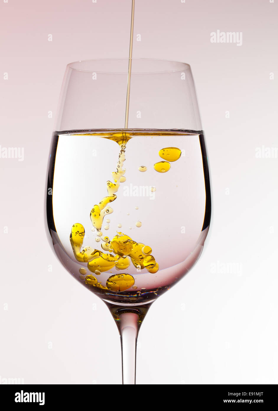 Olio di oliva che viene versato nel bicchiere di vino Foto Stock