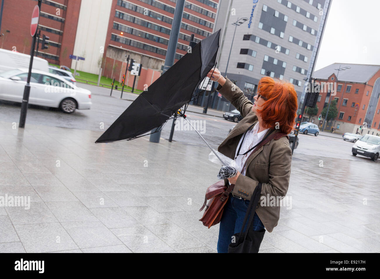 Ombrello, giornata di vento. Persona con un brolly soffiata dentro e fuori dal vento, Liverpool, England, Regno Unito Foto Stock