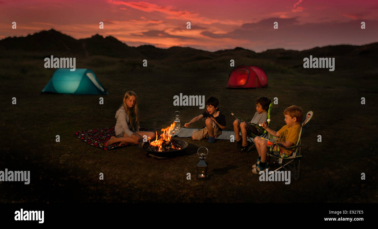 Bambini seduti intorno a un falò tostatura marshmallow Foto Stock