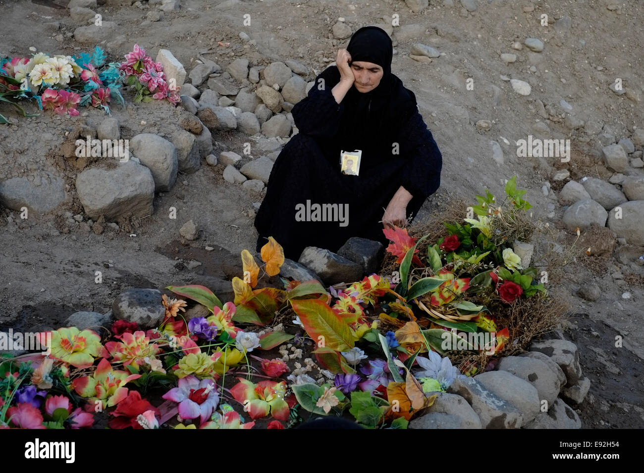 Un mourner guarda sconsolato accanto alla tomba di un combattente di curdi uccisi da uno Stato islamico ISIS o ISIL militanti in un cimitero vicino la città di Al-Malikiyah anche chiamato Derek ( ) curda in Al Hasakah o distretto Hassakeh nella Siria settentrionale Foto Stock