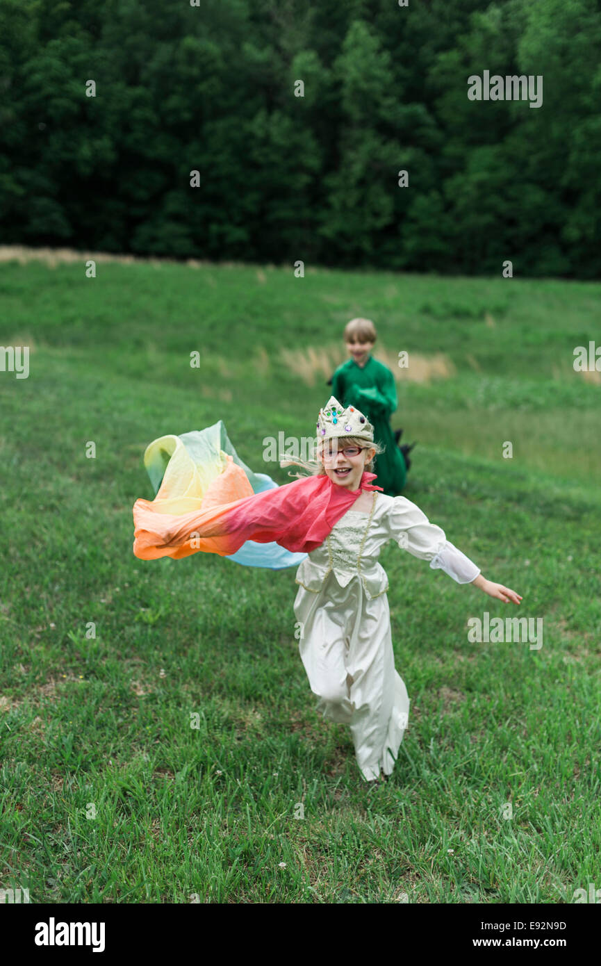 Giovane ragazzo in costume di drago giocando con la fanciulla in Costume principessa in campo erboso Foto Stock