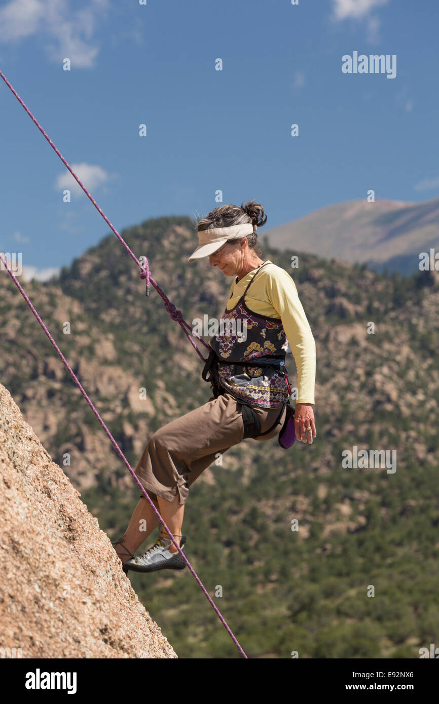Femmina Senior rocciatore scendendo sulla sosta-assisted salire sulle rocce di tartaruga nei pressi di Buena Vista, Colorado, STATI UNITI D'AMERICA Foto Stock