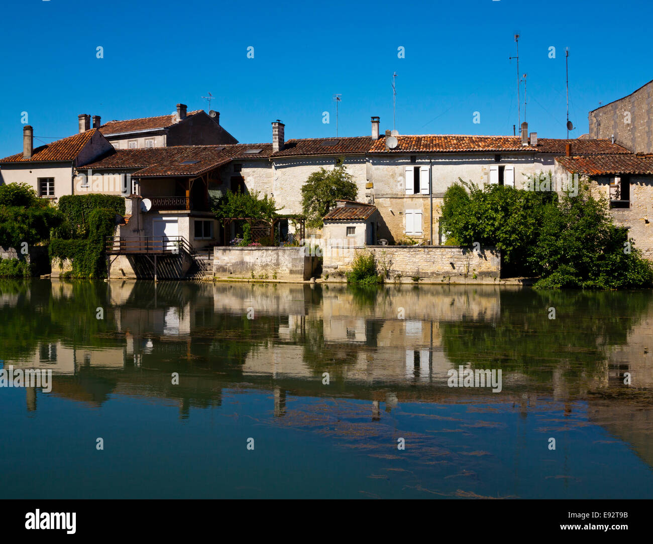 Gli edifici si riflette nel fiume Charente fluente attraverso Jarnac in Charente regione del sud-ovest della Francia Foto Stock