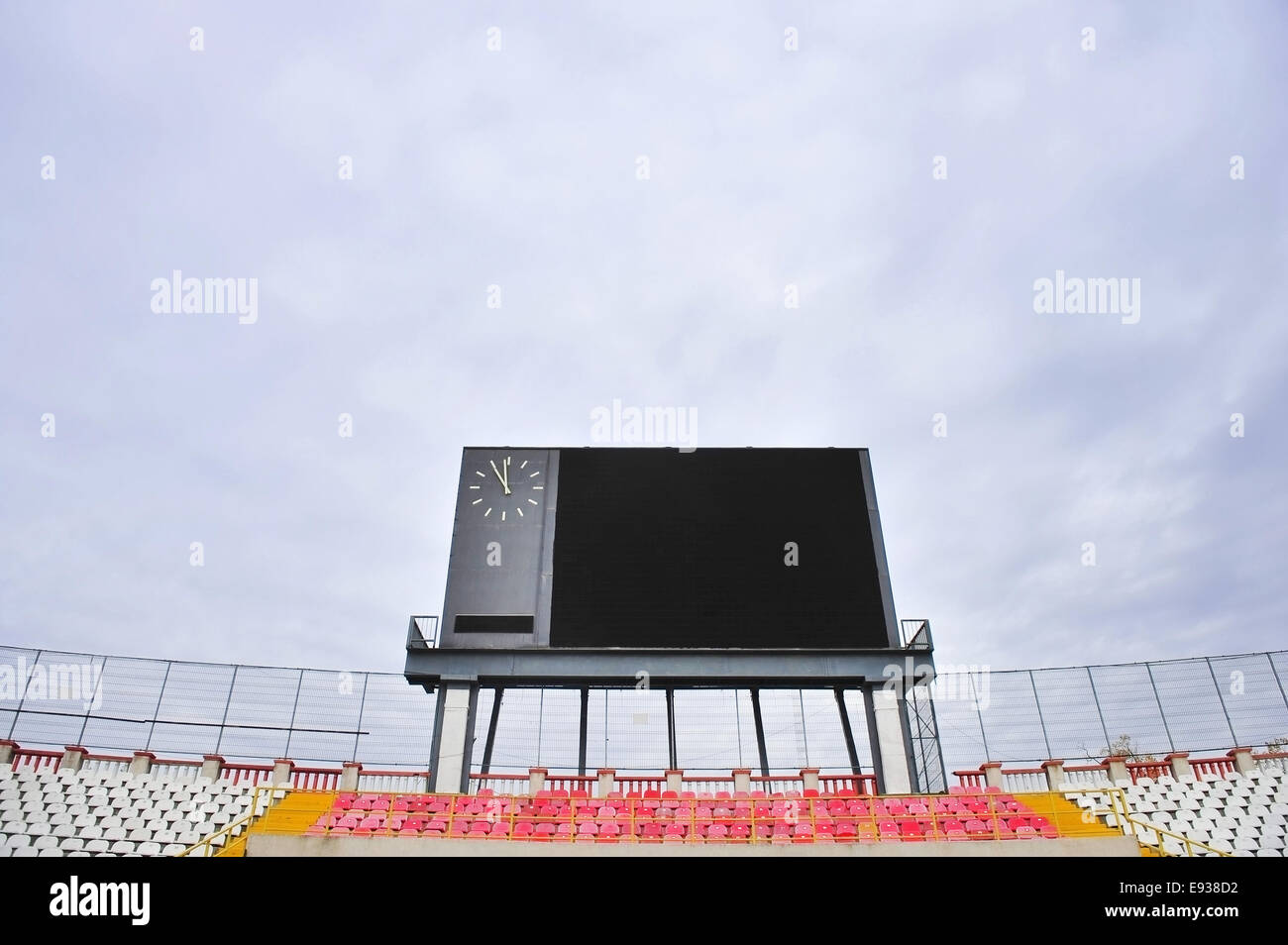 Quadro di valutazione del calcio con orologio e vuoto tribune con cielo nuvoloso sullo sfondo Foto Stock