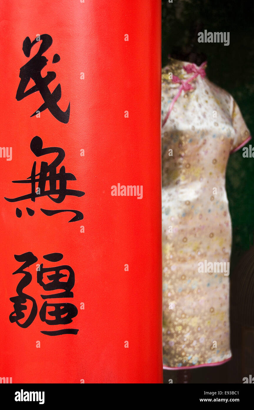 Chiudere verticale fino nero della scrittura cinese su una superficie rossa e una seta Cheongsam abito. Foto Stock