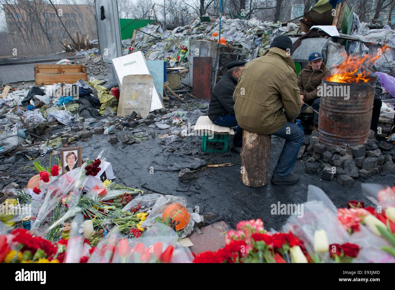 Gli uomini seduti in un braciere accanto a un memoriale per i manifestanti di Maidan morto dal fuoco dei cecchini Foto Stock