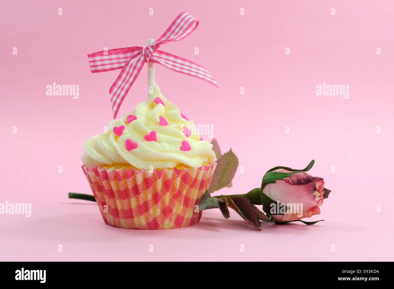 Rosa grazioso cupcake con un pallido rosa seta bocciolo di rosa su sfondo rosa per le femmine di compleanno, matrimoni, Valentino o la festa della mamma. Foto Stock