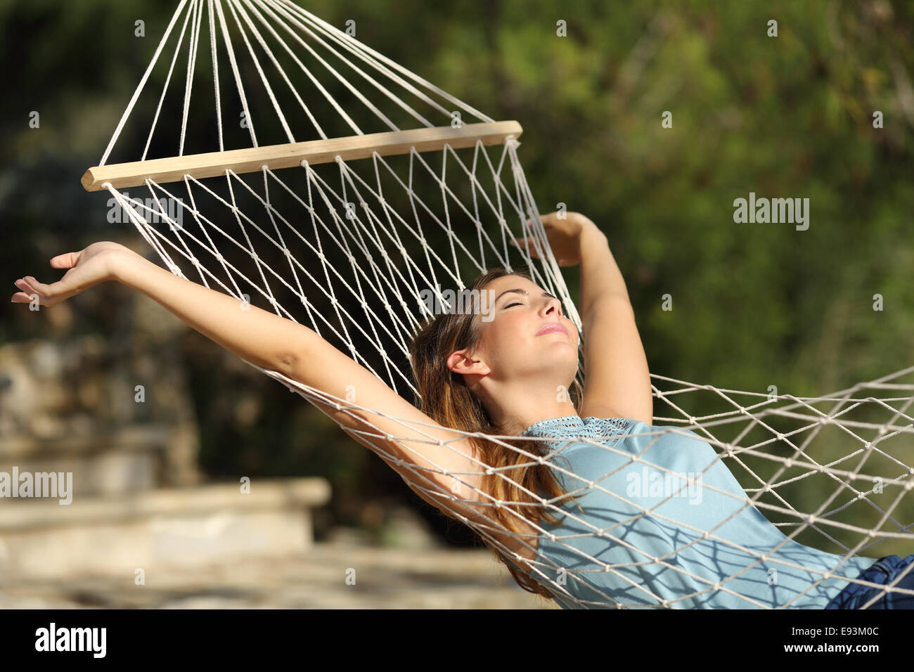 Donna felice relax su una amaca in vacanza e i bracci di sollevamento in montagna Foto Stock