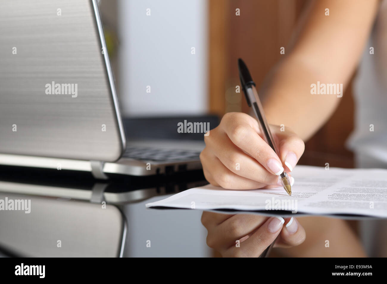 In prossimità di una donna la scrittura a mano di un contratto con un portatile accanto a casa o in ufficio Foto Stock