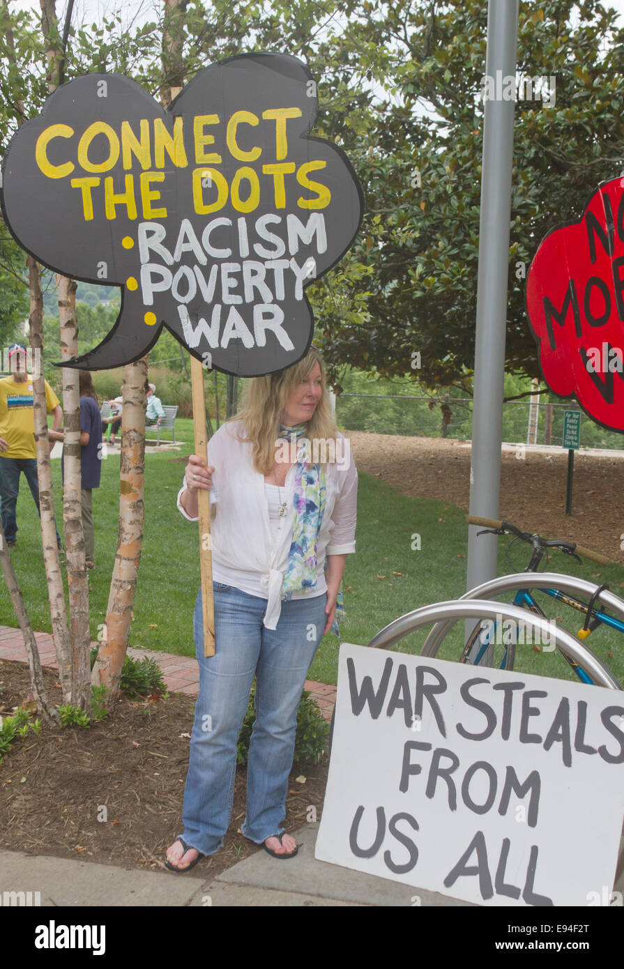Asheville, North Carolina, Stati Uniti d'America - 4 agosto 2014: morale lunedì protester con segno che collega il razzismo, la povertà e la guerra Foto Stock