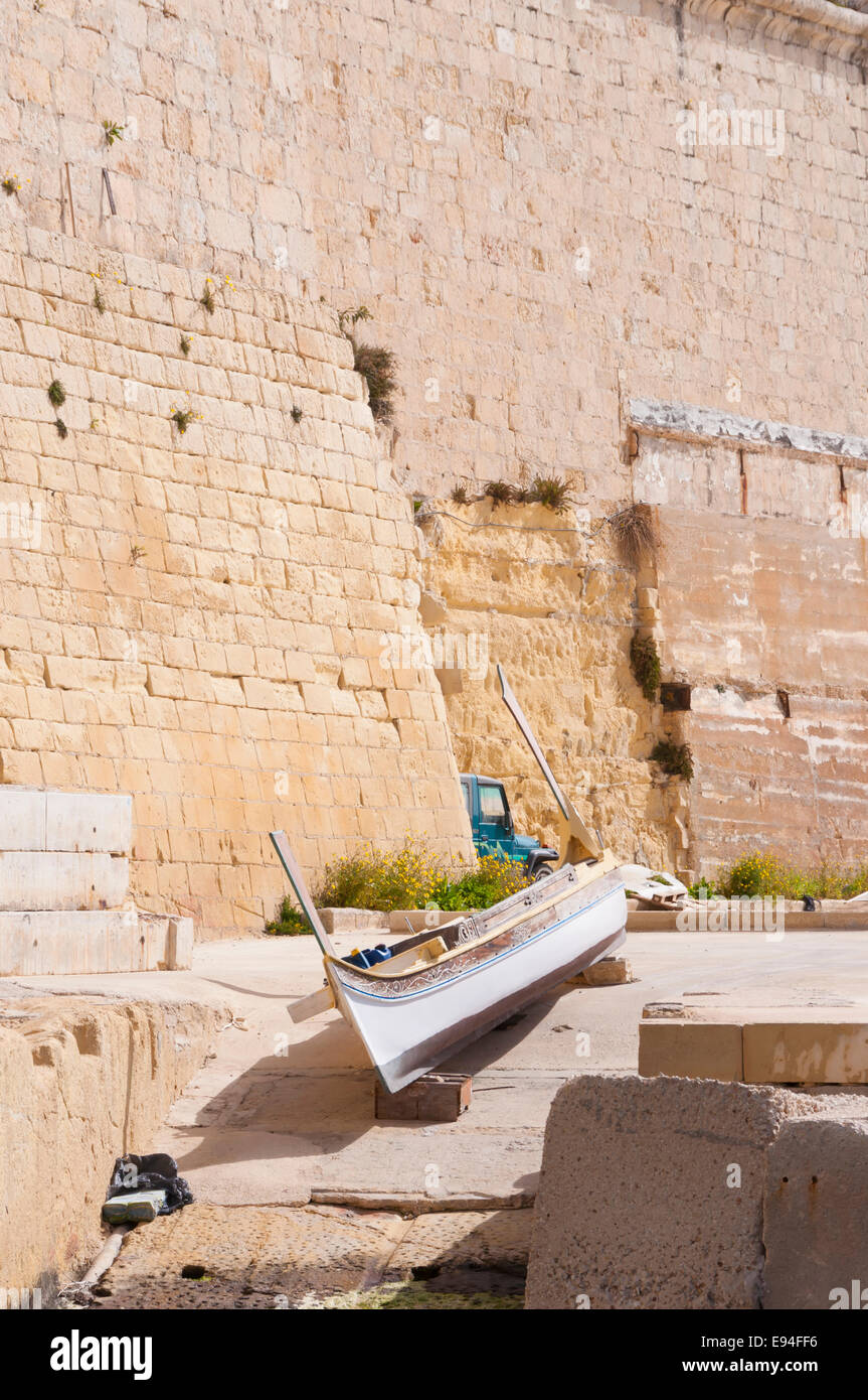 Una tradizionale barca Mantese, chiamato Luzzu su uno scalo al mare a La Valletta, la capitale di Malta Foto Stock