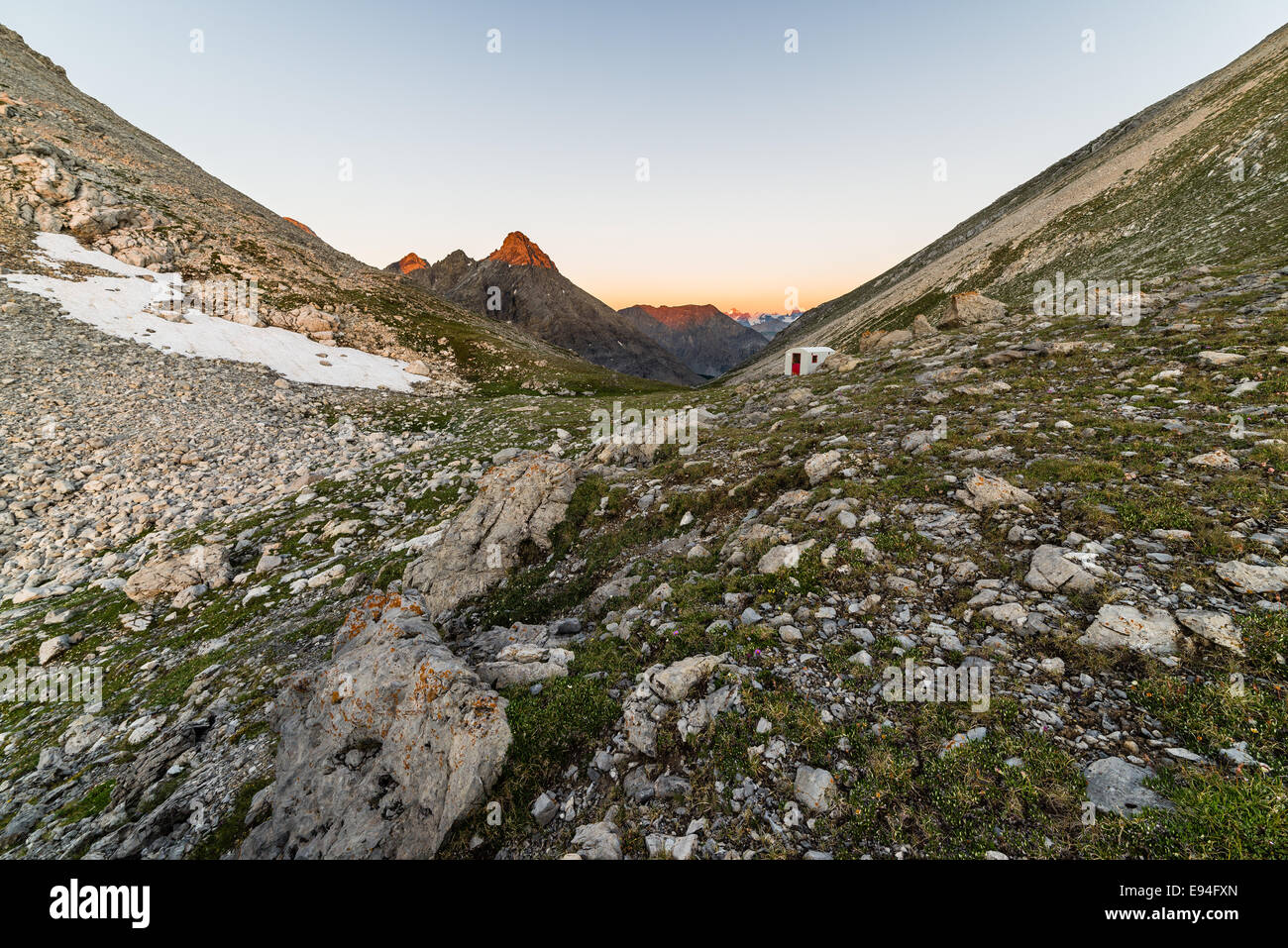 Calda luce rossa a sunrise incandescente le vette più alte dell'italiano - Le Alpi francesi. Piccolo Rifugio di base per l'alloggio. Foto Stock