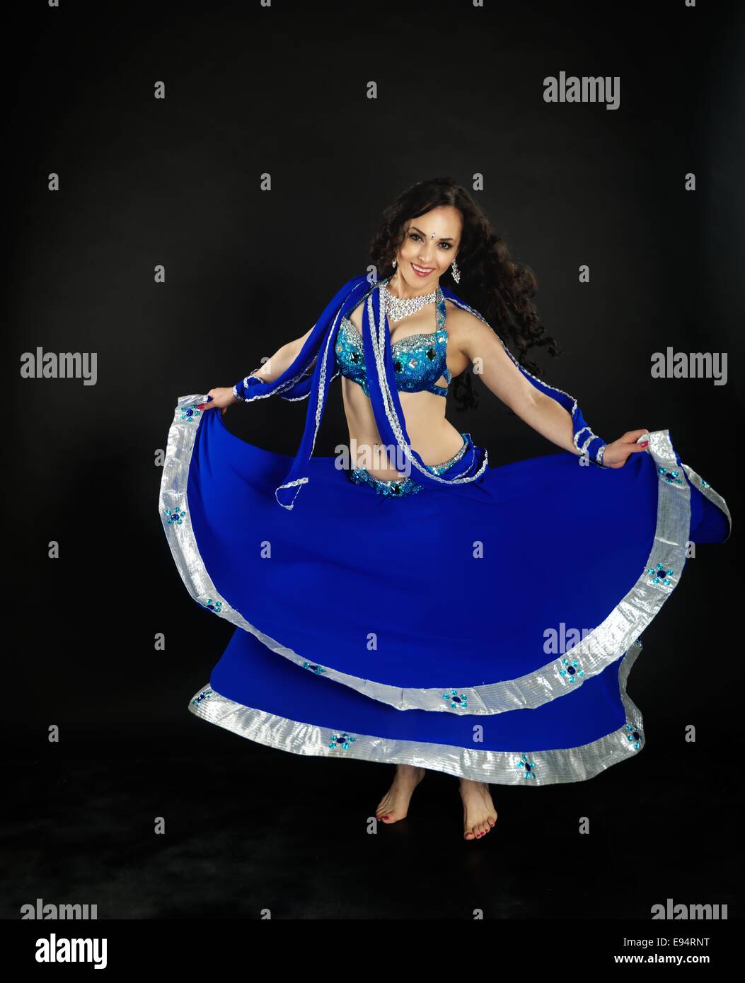 Giovane bella danzatrice del ventre che indossa blu scuro costume di fronte alla parte posteriore in nero di massa. Foto Stock