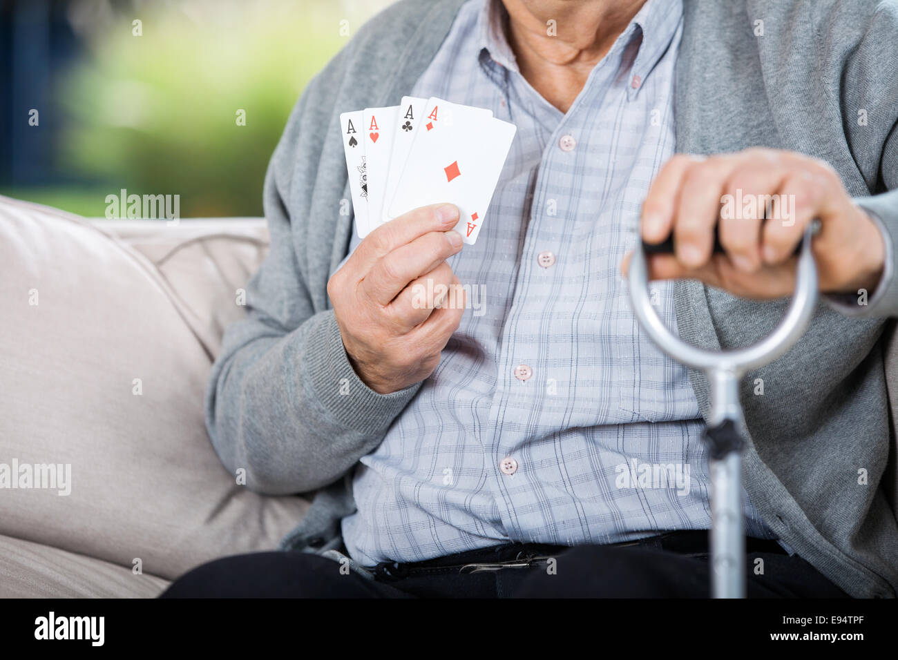 Uomo anziano che mostra quattro assi mentre è seduto Foto Stock