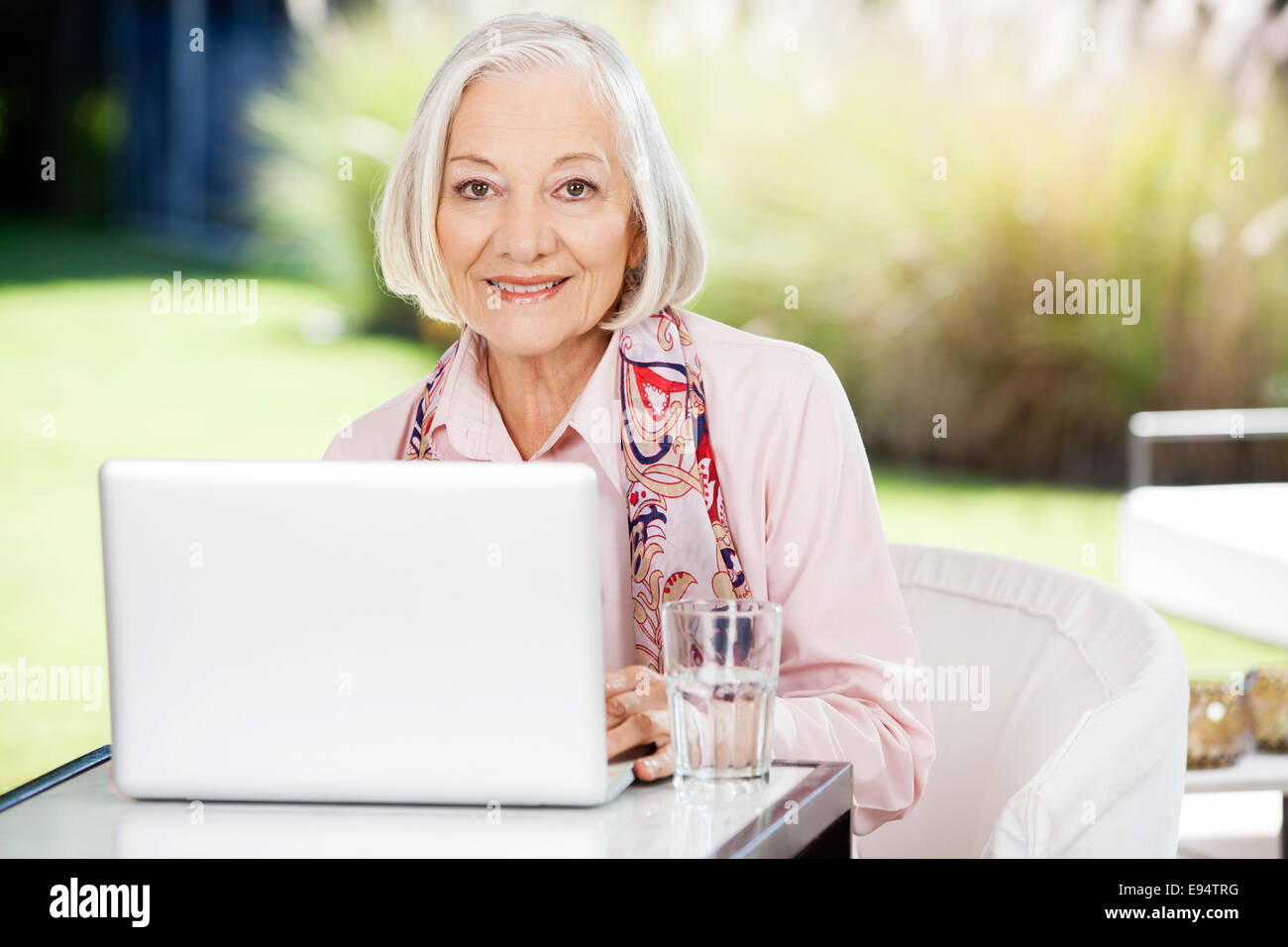 Senior donna utilizzando computer portatile presso la casa di cura portico Foto Stock