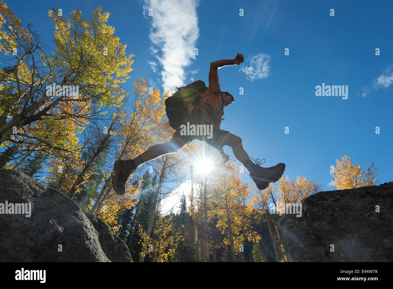 Backpacker saltando da boulder a boulder su un astragalo in pendenza dell'Oregon Mountians Wallowa. Foto Stock