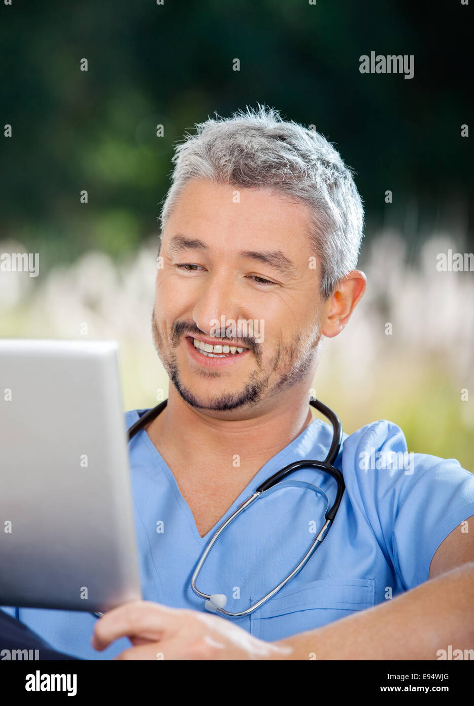 Custode maschio sorridere mentre guardando il computer tablet Foto Stock