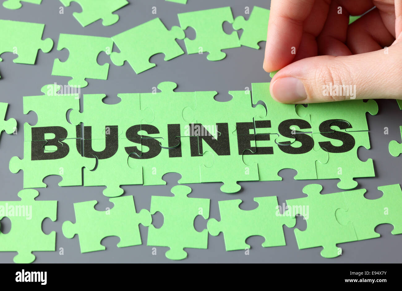 Donna di mano completando puzzle con la parola 'business'. Foto Stock