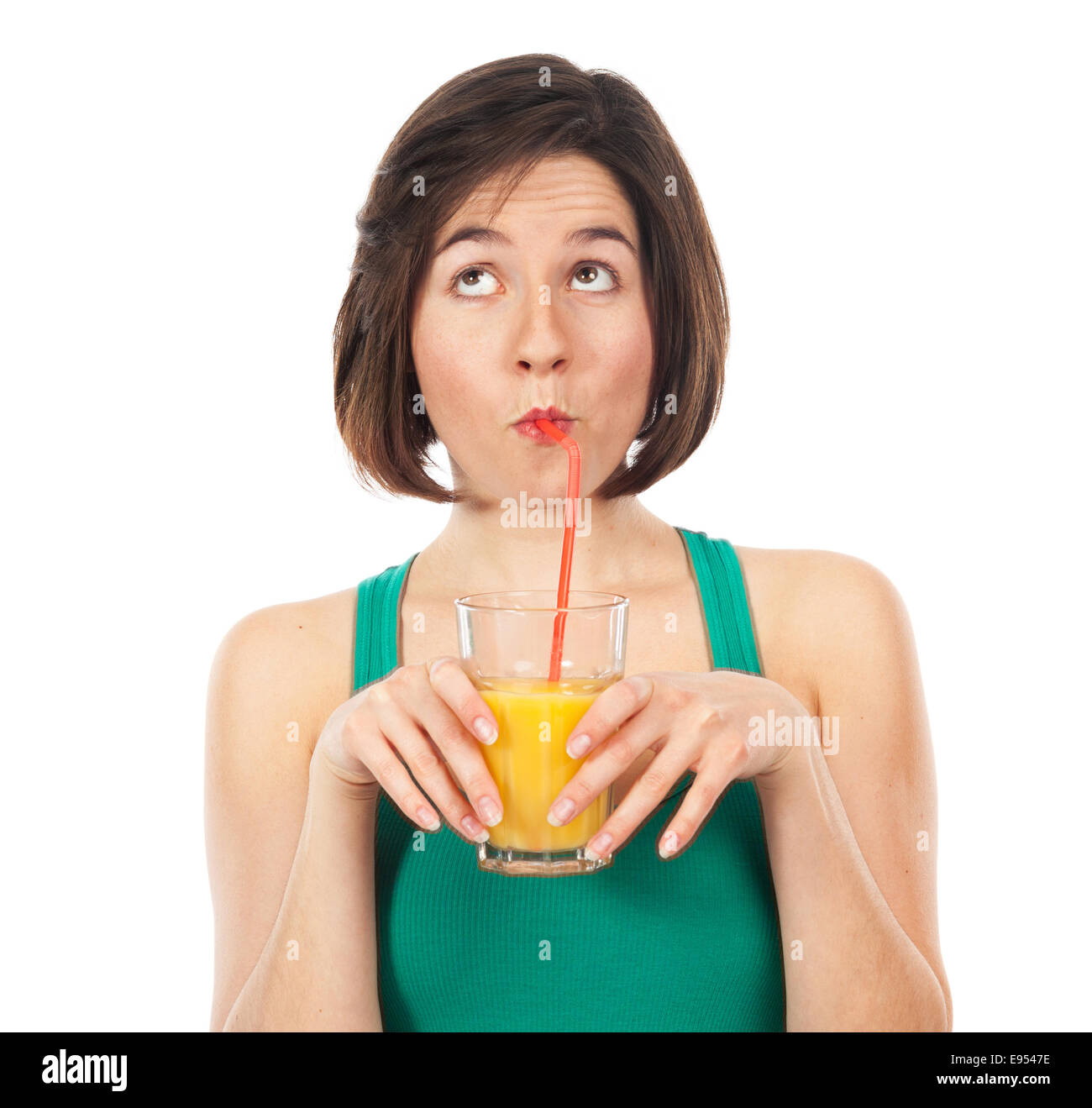 Ritratto di una giovane donna di bere un succo di arancio con una cannuccia e guardando in alto isolato su bianco Foto Stock