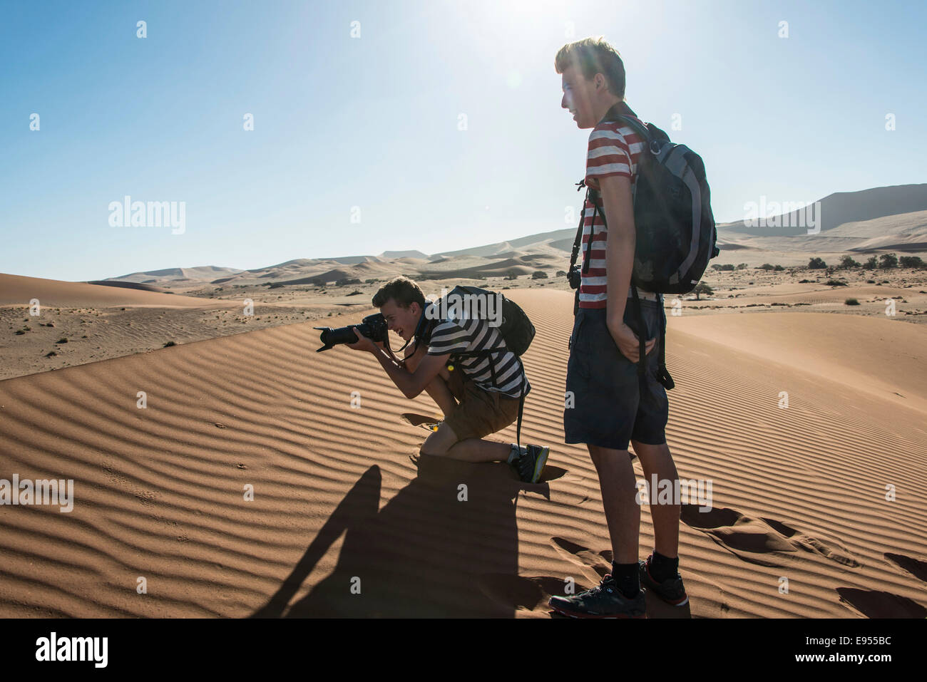 Due ragazzi in piedi su una duna, scattare foto, Sossusvlei, Namib Desert, Regione di Hardap, Namibia Foto Stock